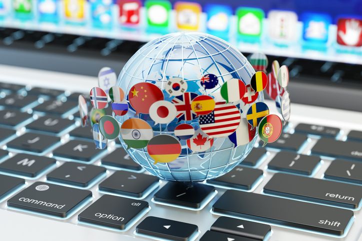 small globe with several country flags resting on a keyboard