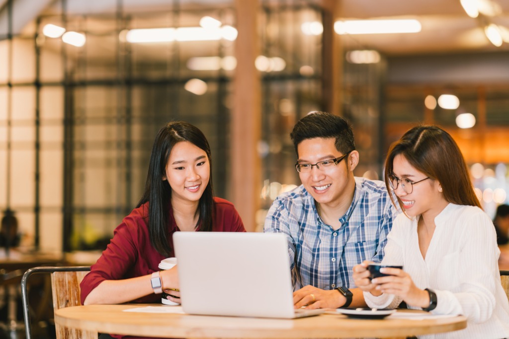 chinese co-workers gathered around a laptop