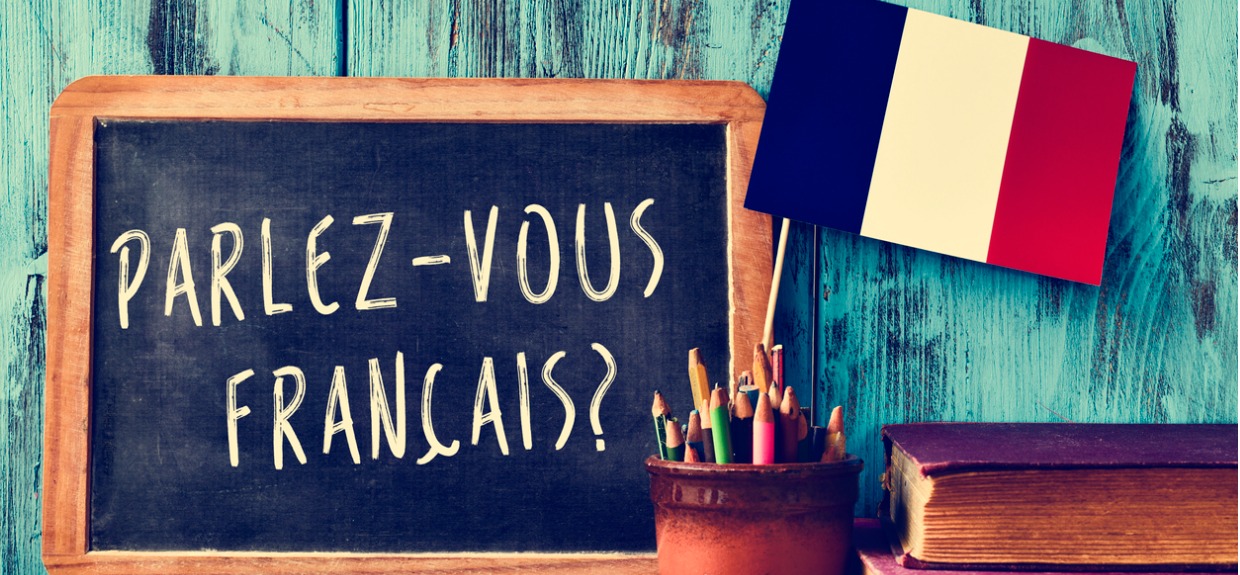 parlez-vous francais written on chalkboard next to french flag on desk